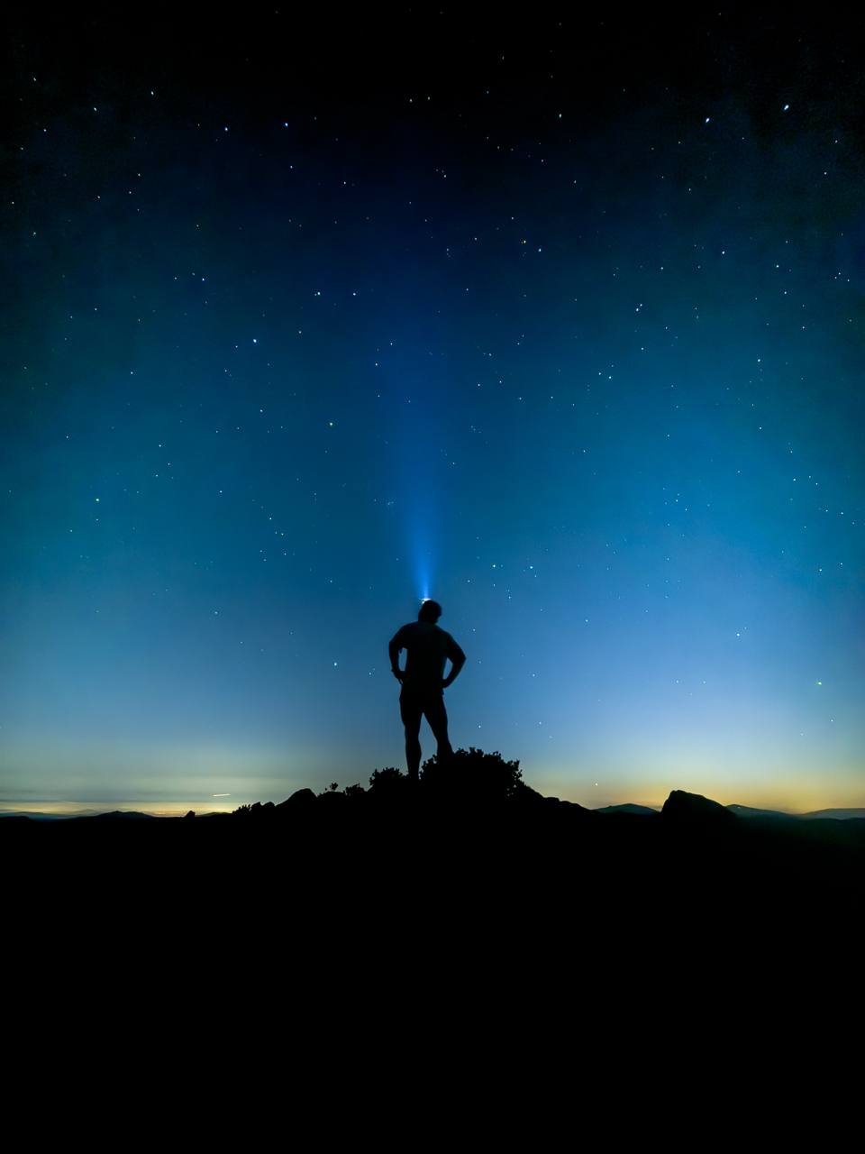 Sam Blaze standing on a summit at altitude under a star-filled night sky.